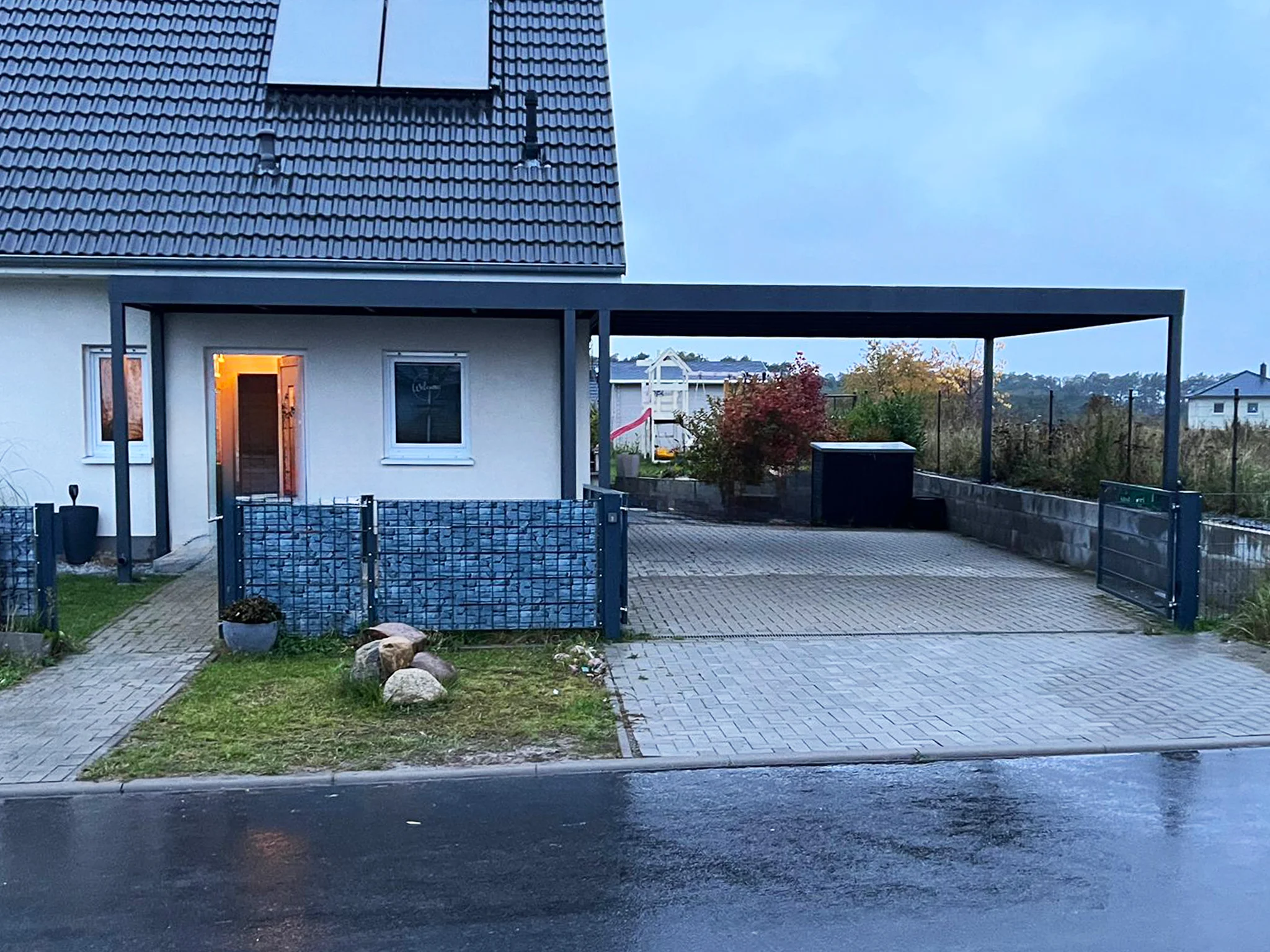 Carport mit Flachdach und integrierter Entwässerung neben Gabionenzaun – Leverkusen