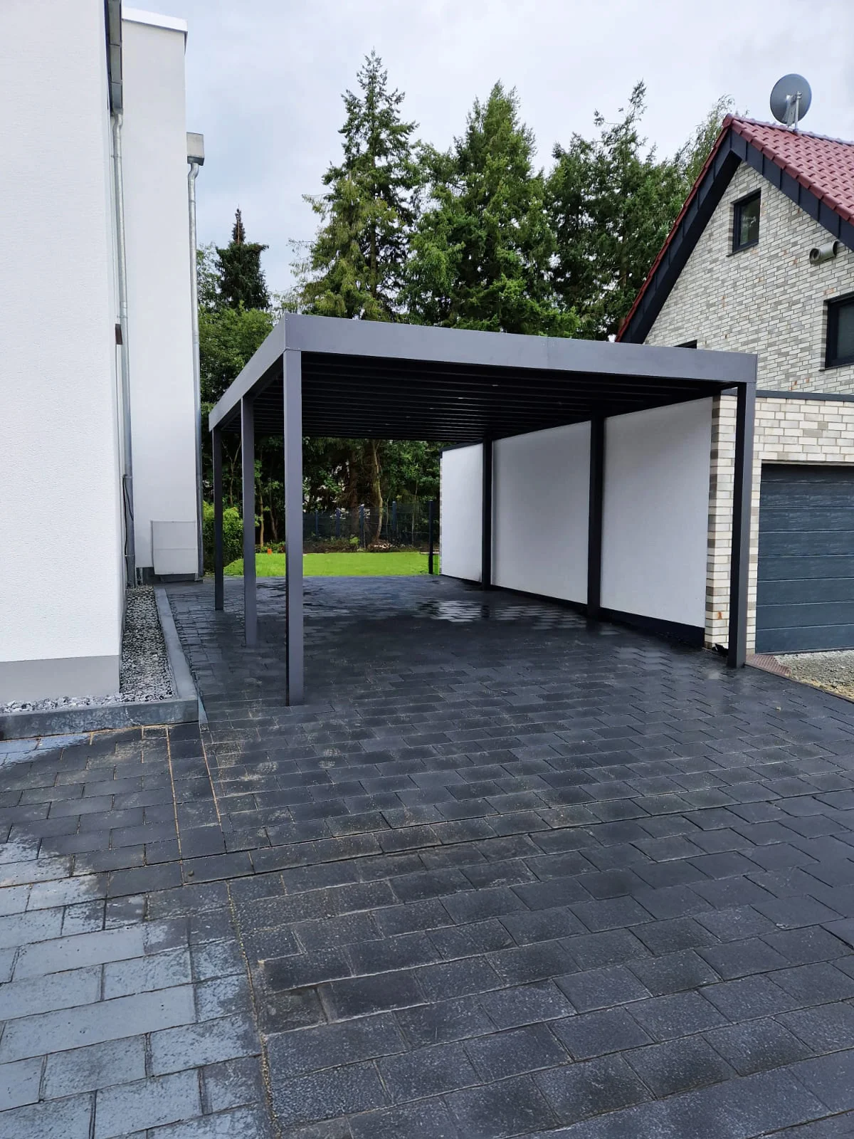 Doppelcarport mit weißen Sichtschutzpaneelen Dunkelpflaster Köln