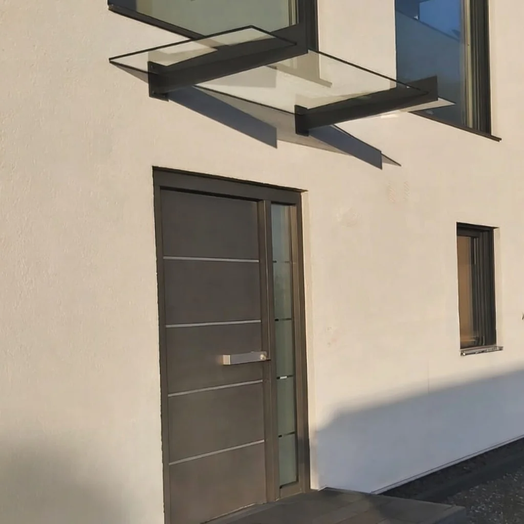 Filigranes Glasvordach mit Wandhaltern an modernem Eingangstor in Burscheid