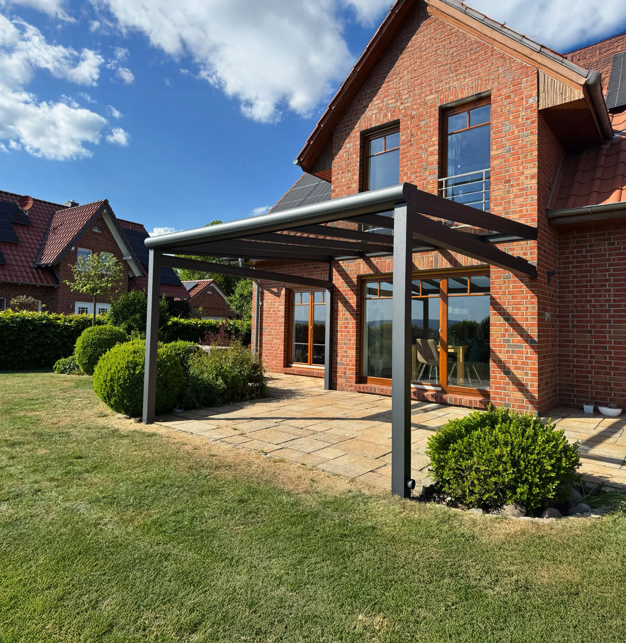 Terrassenüberdachung aus Glas und Aluminium an einem Klinkerhaus, Referenz aus Leverkusen